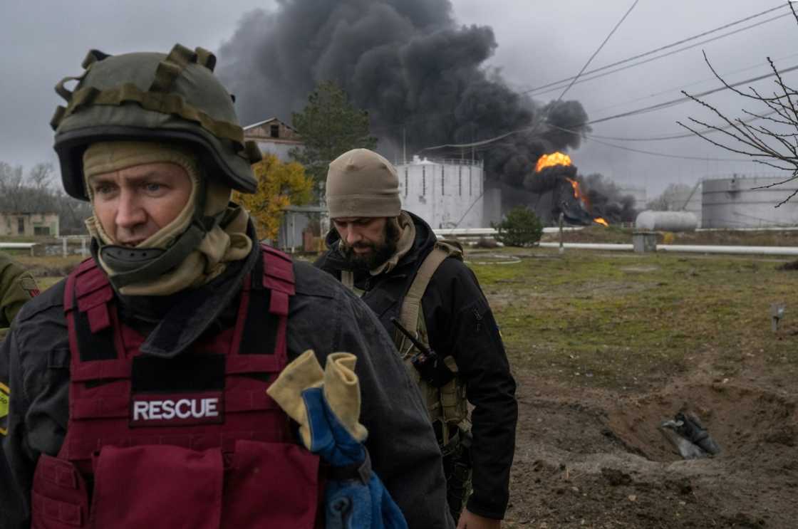 A Ukrainian rescue service member and a soldier inspect the area as black smoke rises from an oil reserve in Kherson A Ukrainian rescue service member and a soldier inspect the area as black smoke rises from an oil reserve in Kherson