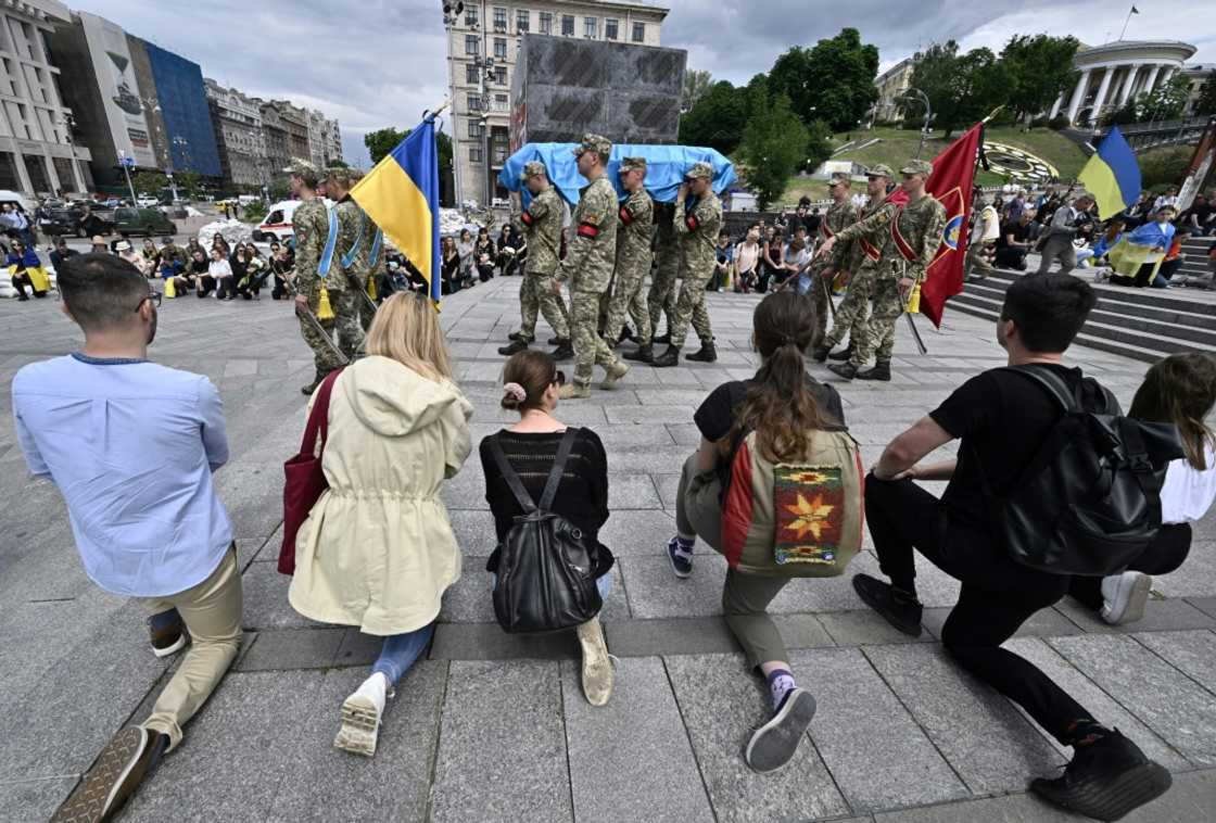 Mourners approached the body in turn, kneeling or bowing and placing a hand on the coffin where many flowers were laid Mourners approached the body in turn, kneeling or bowing and placing a hand on the coffin where many flowers were laid