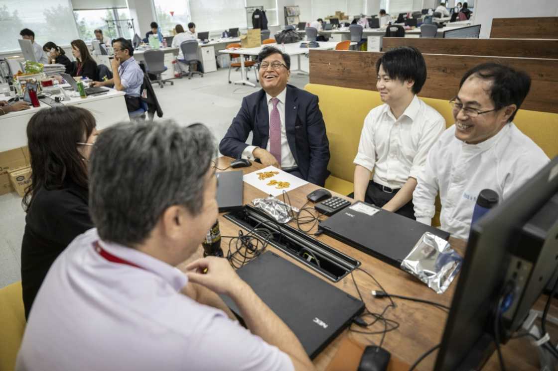 Lekh Juneja (C), chatting with employees while testing samples of rice crakers at the company's headquarters in Niigata city, Niigata prefecture