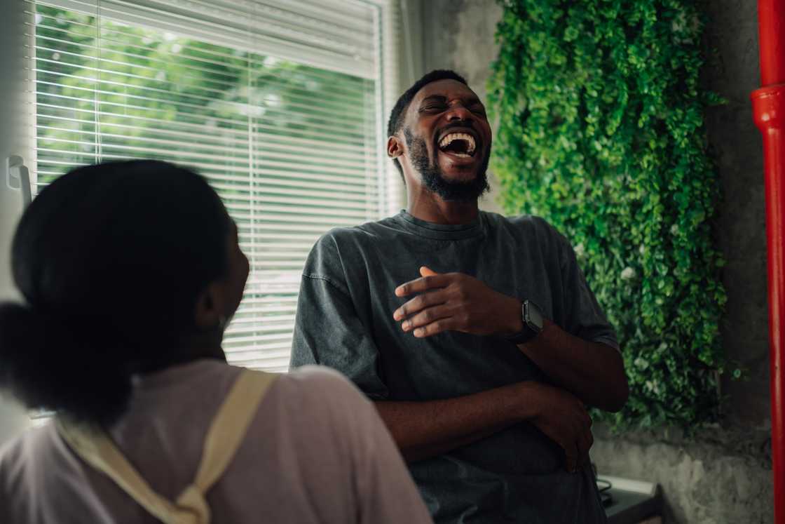 A man and woman laughing joyfully inside a cozy home A man and woman laughing joyfully inside a cozy home