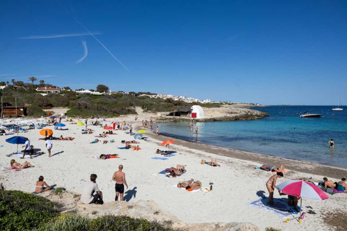 Tourists are flocking to Spain in record numbers, such as these seen sunbathing on the island of Menorca, giving the economy a huge boost Tourists are flocking to Spain in record numbers, such as these seen sunbathing on the island of Menorca, giving the economy a huge boost