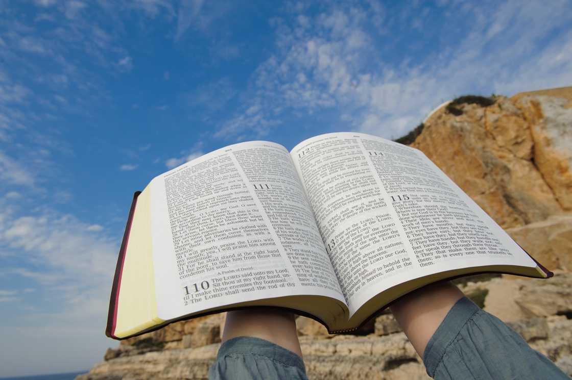 A woman with open Bible in their hands raised to heaven A woman with open Bible in their hands raised to heaven