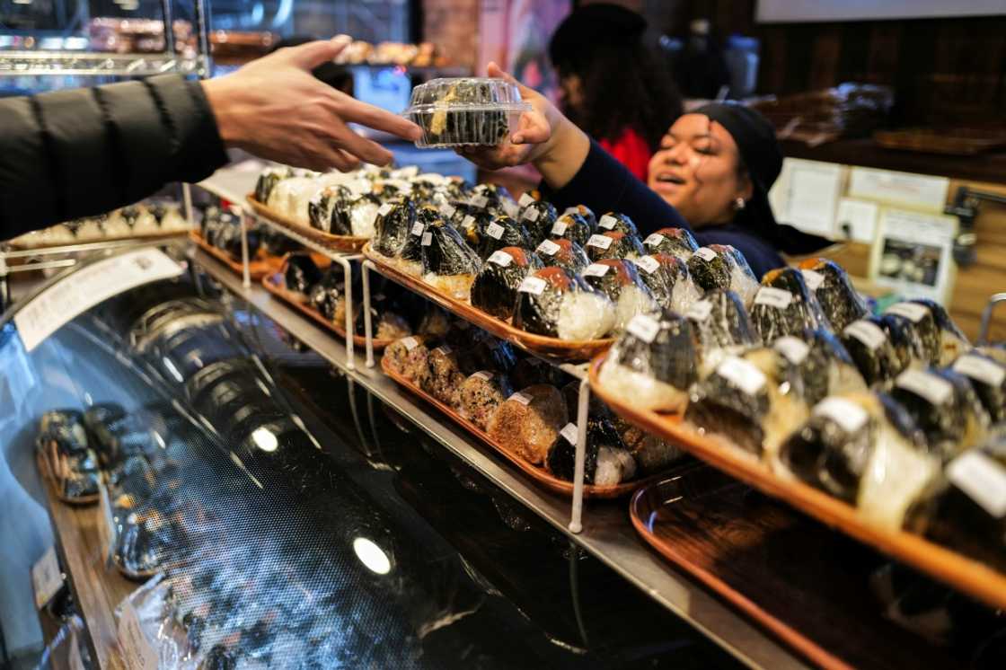 A customer (L) buys a stuffed rice ball, known as "onigiri", at the Omusubi Gonbei shop in Manhattand. A customer (L) buys a stuffed rice ball, known as "onigiri", at the Omusubi Gonbei shop in Manhattand.
