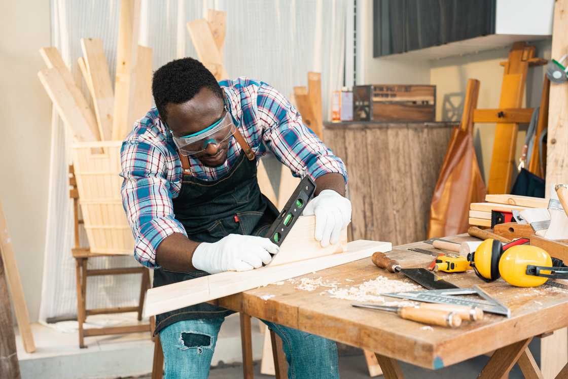 A carpenter uses a power tool on a wooden table.