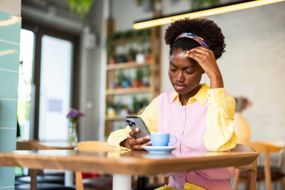 A stressed woman while using a smartphone in a coffee shop A stressed woman while using a smartphone in a coffee shop