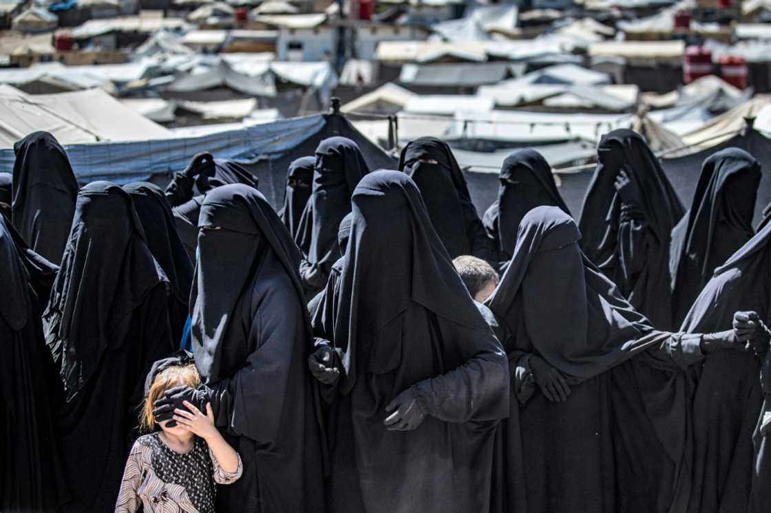 Women and a child queue to receive aid at the Kurdish-run al-Hol camp for relatives of suspected Islamic State group fighters in Syria Women and a child queue to receive aid at the Kurdish-run al-Hol camp for relatives of suspected Islamic State group fighters in Syria