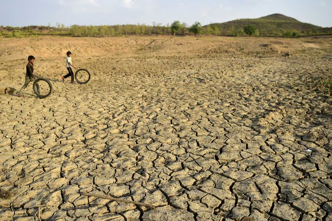 Children play with discarded cycle tyres as they walk on a dried up pond in Agrotha Children play with discarded cycle tyres as they walk on a dried up pond in Agrotha