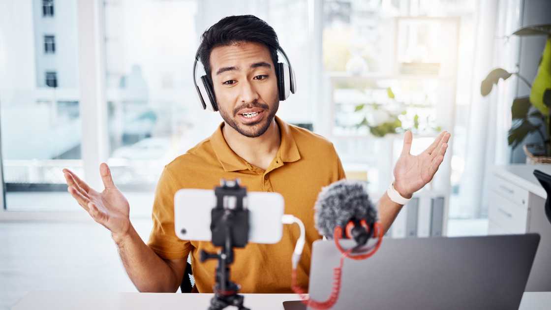 A male content creator is recording a broadcast in his home office