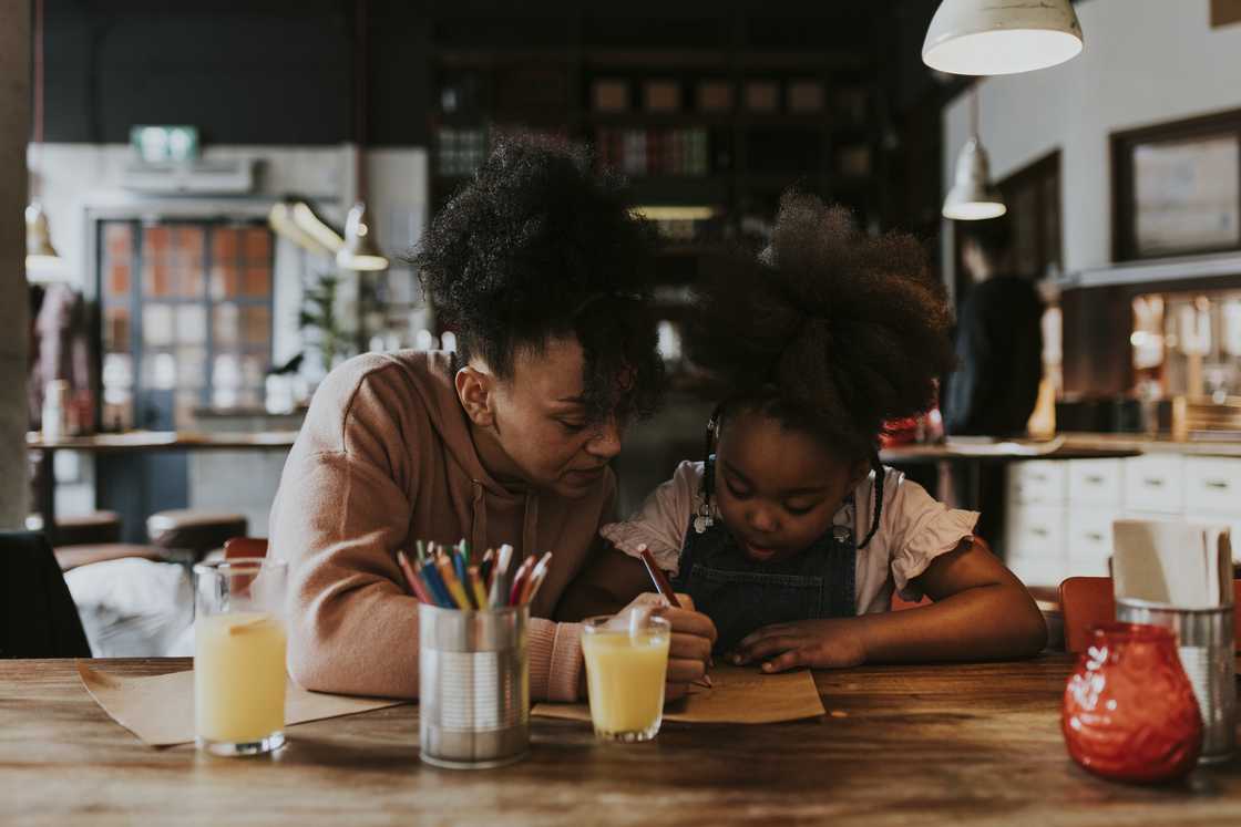 A mother helping her young daughter with homework.