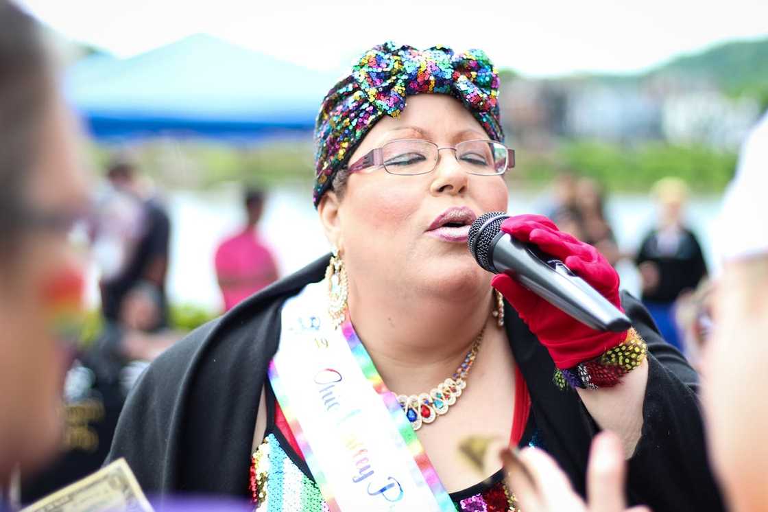 A woman speaks into a microphone at an outdoor event.