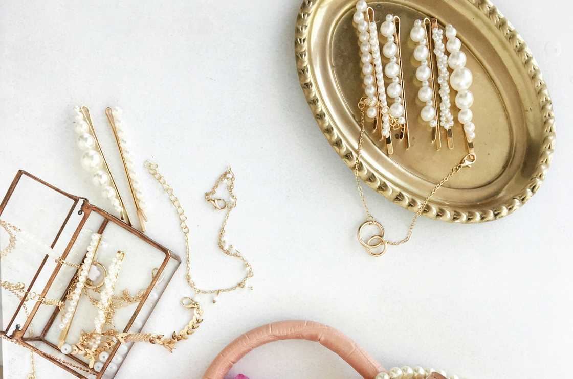Pieces of jewellery on a gold dish on a white surface
