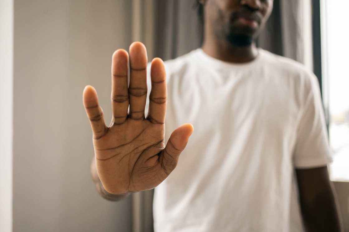 A person holds up an open hand in a stop gesture. A person holds up an open hand in a stop gesture.