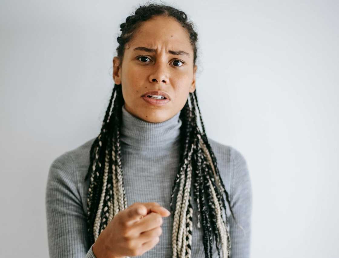 A woman points forward with a tense, accusing expression.