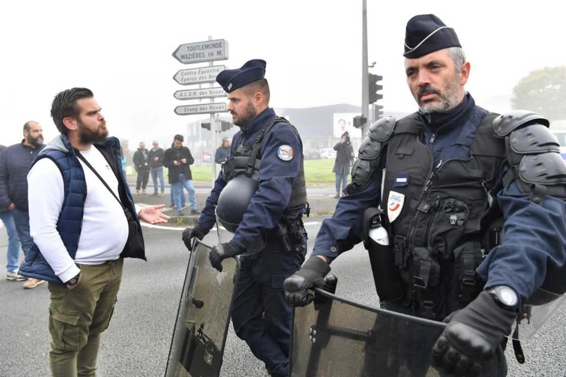 A worker talks to police officers during a demonstation at the Michelin plant in Cholet, western France