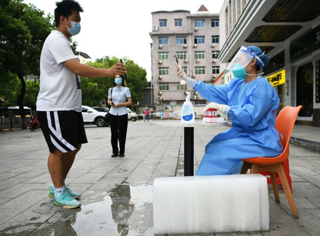 A health worker preparing Covid tests sits next to a block of ice in an attempt to cool off as China bakes under record temperatures A health worker preparing Covid tests sits next to a block of ice in an attempt to cool off as China bakes under record temperatures