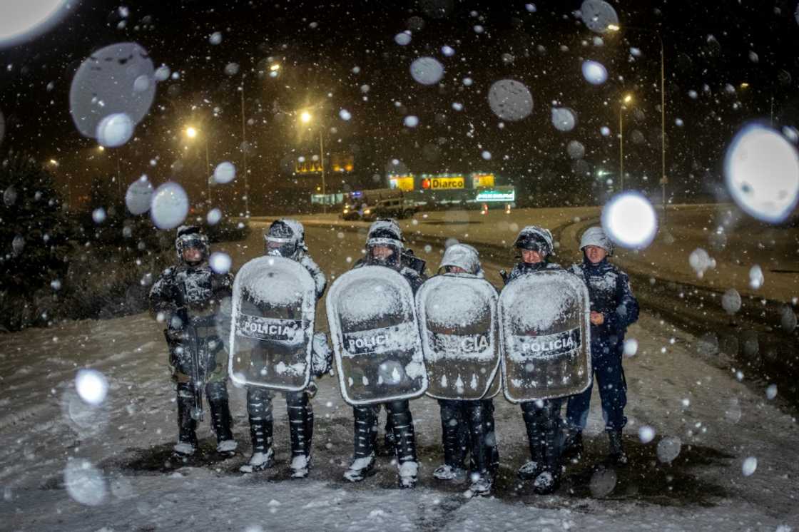 Police officers guard a Diarco supermarket under falling snow after an attempted looting Police officers guard a Diarco supermarket under falling snow after an attempted looting