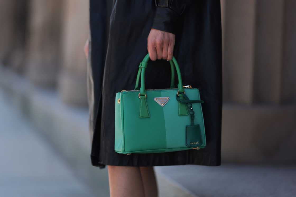 A woman in a black dress holding a Prada green Saffiano colourful Galleria bag.