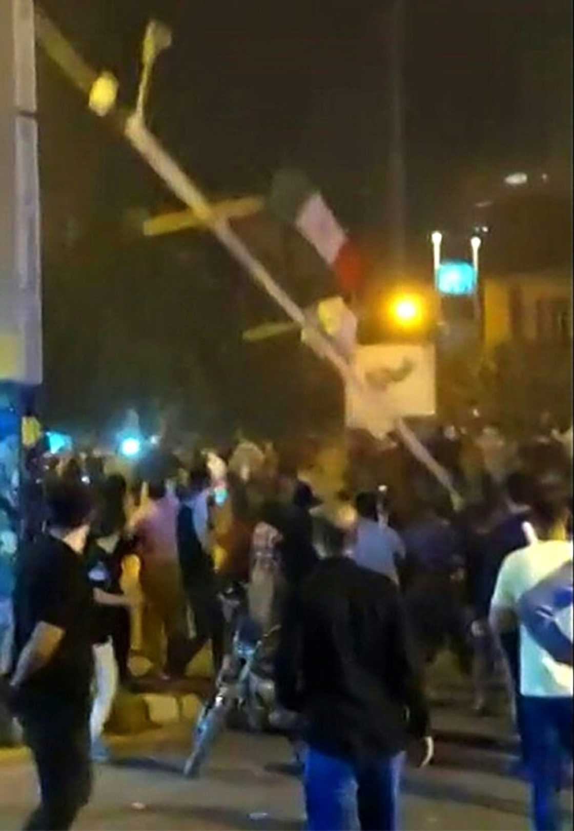 This grab from a video made available on the ESN platform shows protesters bring down a flagpole in Saqez city of Iran's Kurdistan province on September 19, 2022 This grab from a video made available on the ESN platform shows protesters bring down a flagpole in Saqez city of Iran's Kurdistan province on September 19, 2022