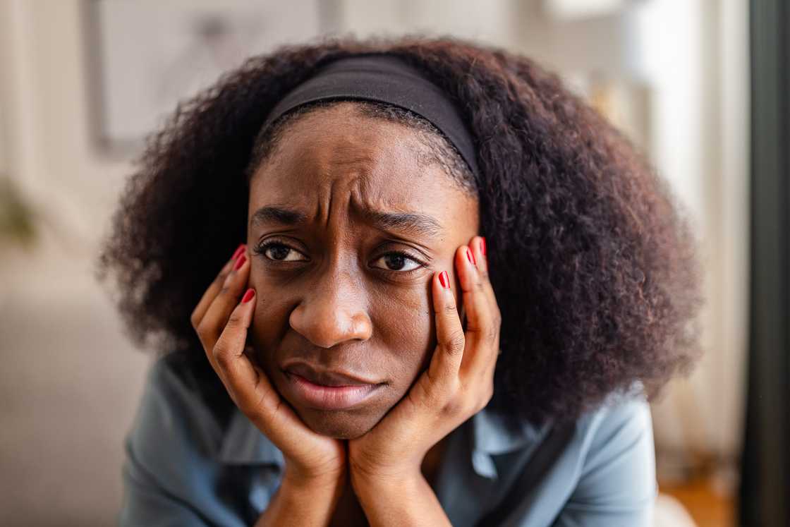 A young woman sitting indoors with a concerned expression