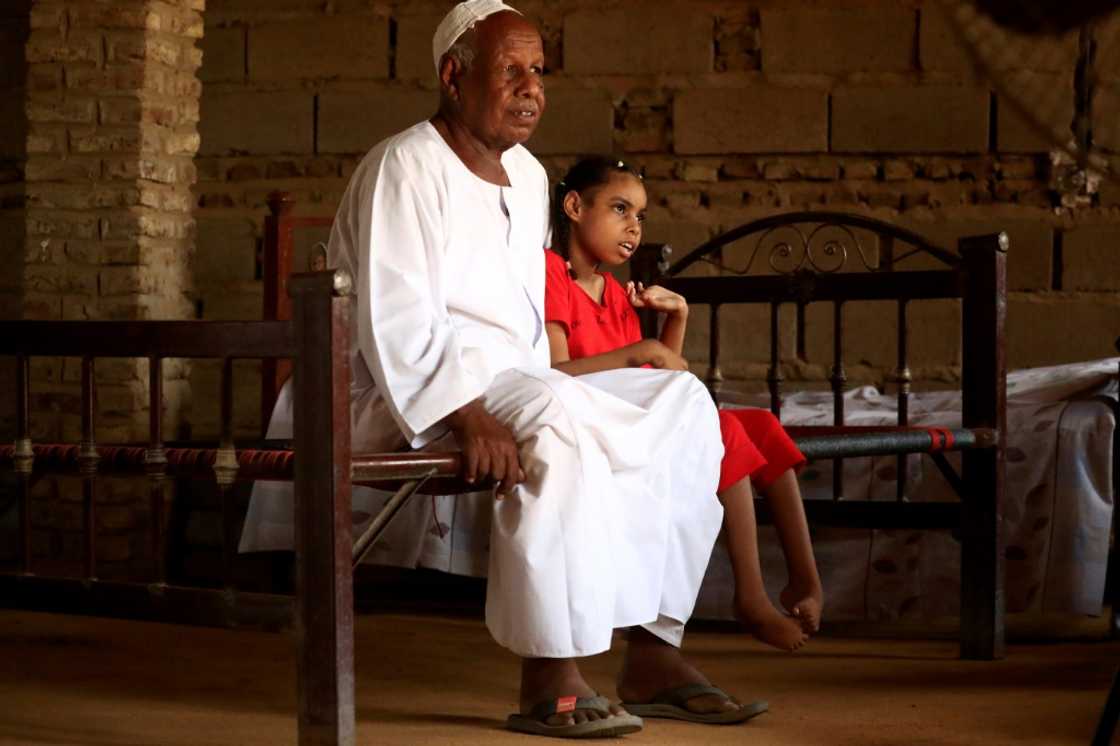 Nafisa, 8, who is unable to walk, is pictured sitting next to her father in the village of Banat Nafisa, 8, who is unable to walk, is pictured sitting next to her father in the village of Banat