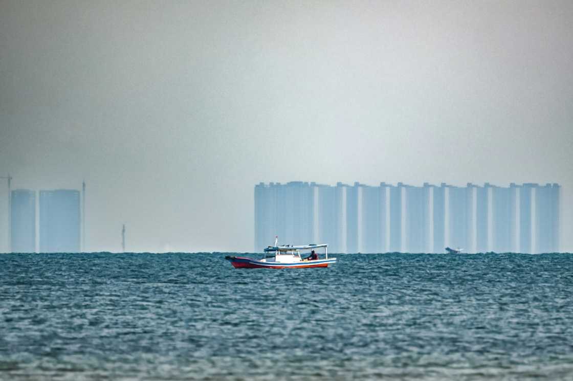 A man fishes off Pari, as buildings located in the northern part of nearby Jakarta are seen in the distance A man fishes off Pari, as buildings located in the northern part of nearby Jakarta are seen in the distance