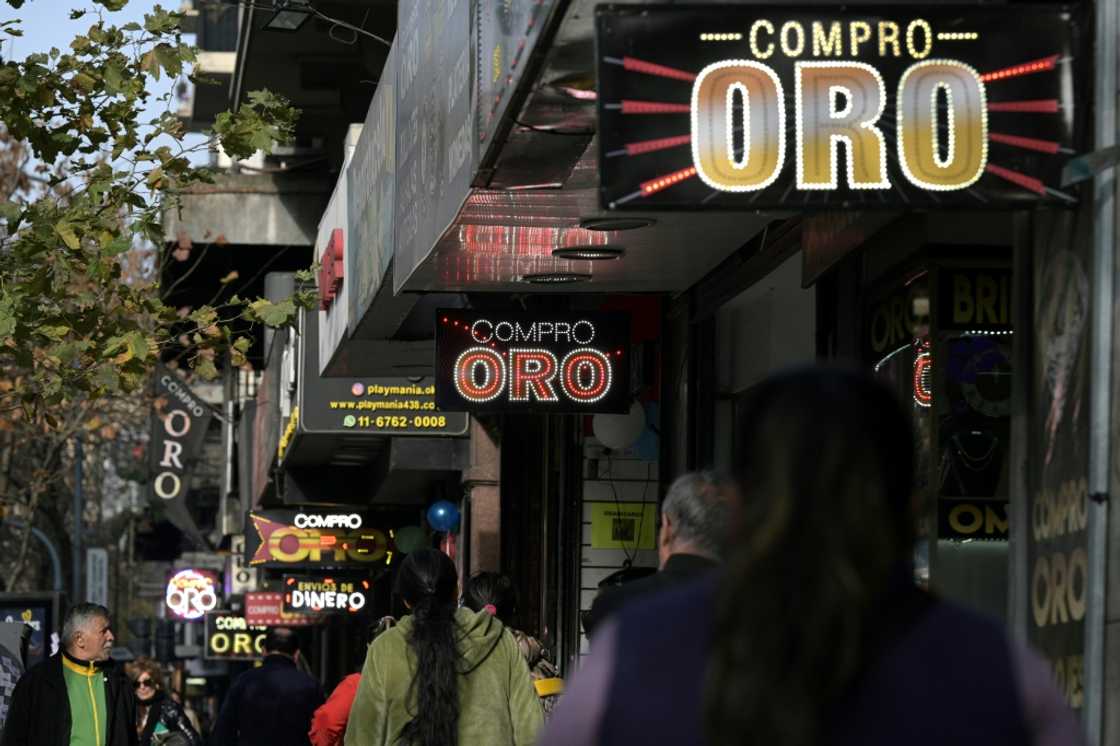 Pedestrians walk past gold dealerships in Buenos Aires