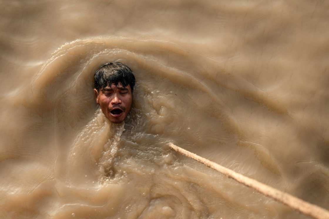 A man swims after a dive to recover a sunken ship in the Yangon River; scrap dealers buy the metal and melt it down to be used again A man swims after a dive to recover a sunken ship in the Yangon River; scrap dealers buy the metal and melt it down to be used again