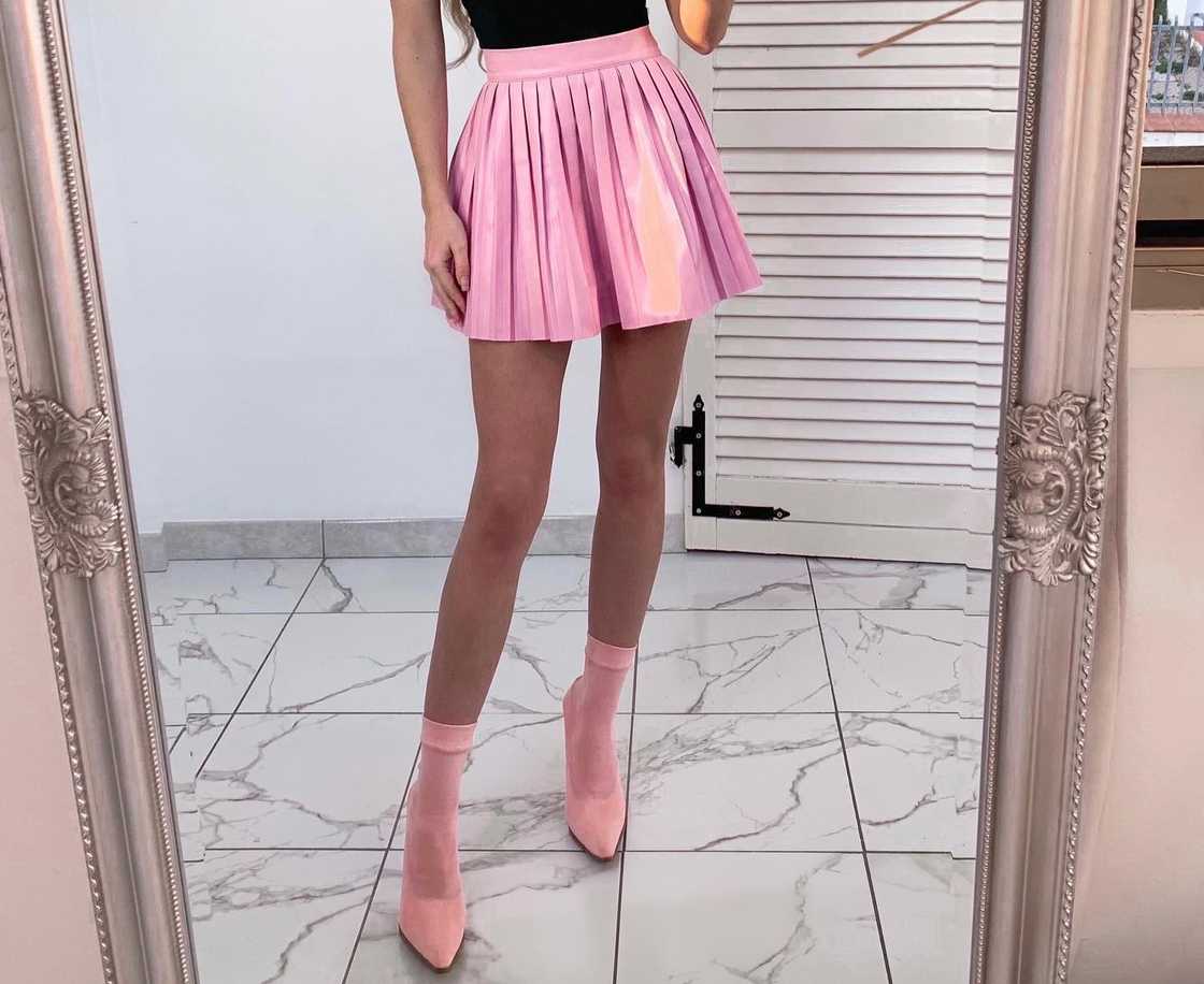 A fashionable woman matches a pink skater skirt with pink boots A fashionable woman matches a pink skater skirt with pink boots