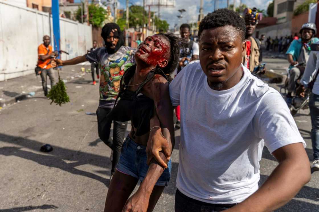 A man assists an injured woman during a protest against Haitian Prime Minister Ariel Henry calling for his resignation, in Port-au-Prince, October 10, 2022 A man assists an injured woman during a protest against Haitian Prime Minister Ariel Henry calling for his resignation, in Port-au-Prince, October 10, 2022