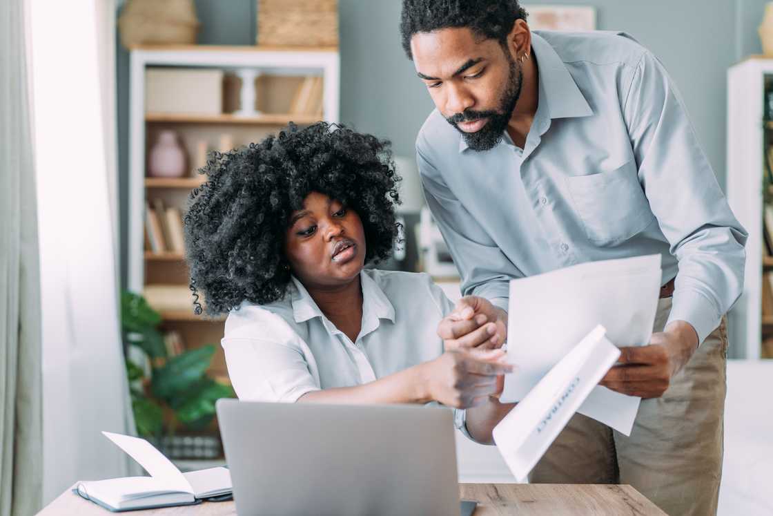 One partner shows papers to another partner. One partner shows papers to another partner.