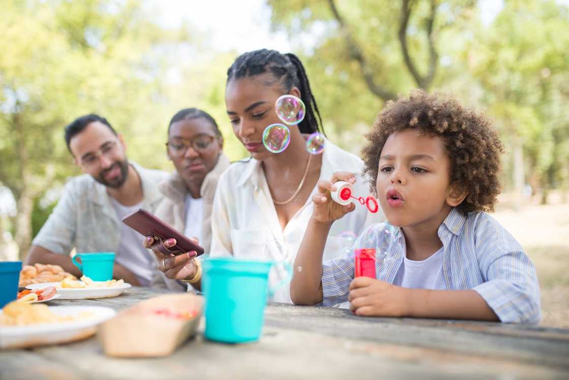 A backyard family cookout with kids playing and adults conversing.
