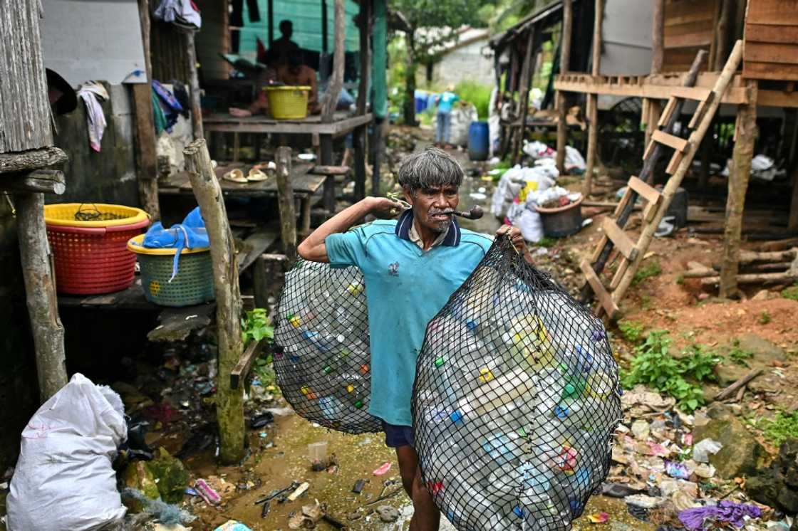 A Moken fisherman carries bags of plastic waste to sell to Tide staff members at his fishing village on Thailand's southern island of Koh Chang