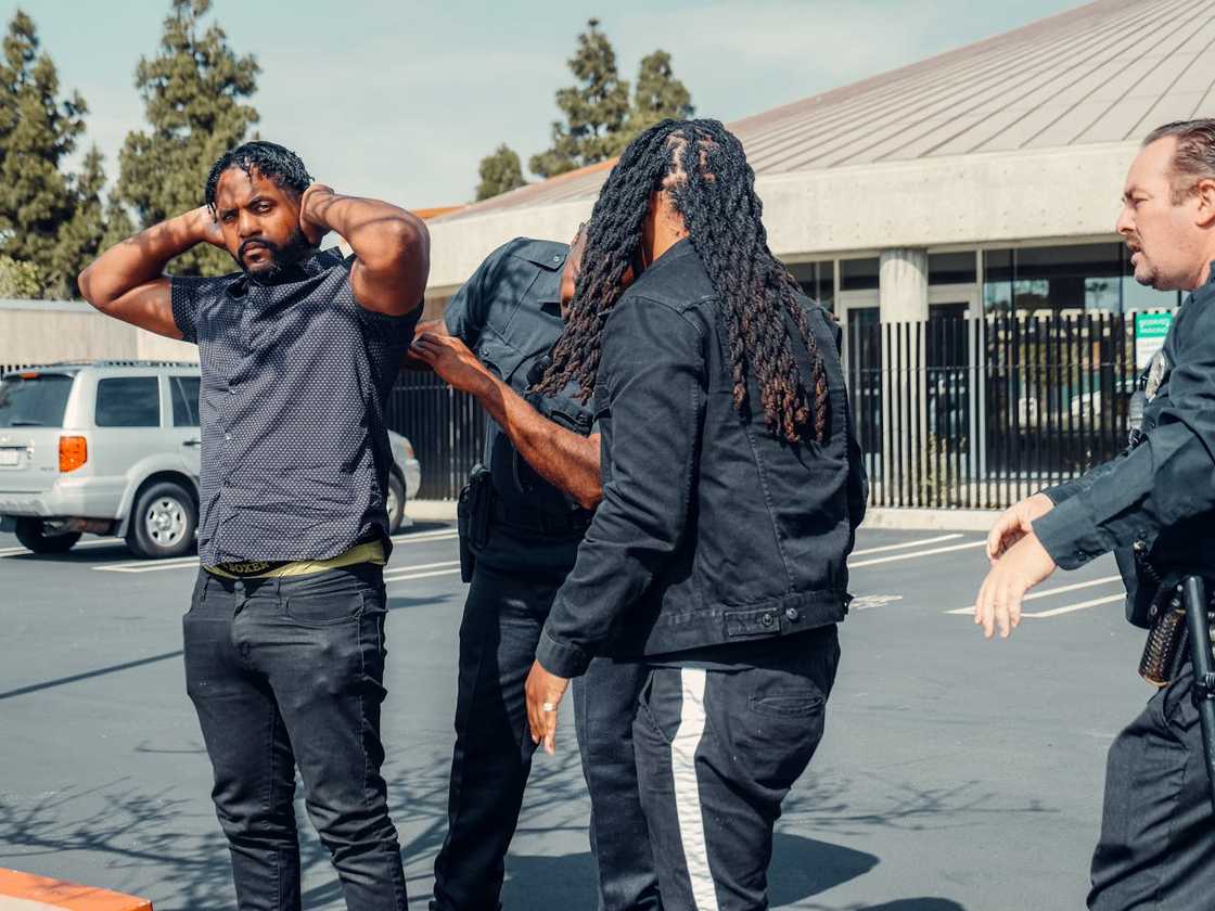 Officers escorts a man toward a patrol car outside.
