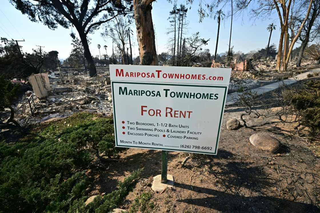 The remains of townhomes destroyed by the Eaton Fire lie behind an advertising sign in Altadena, California