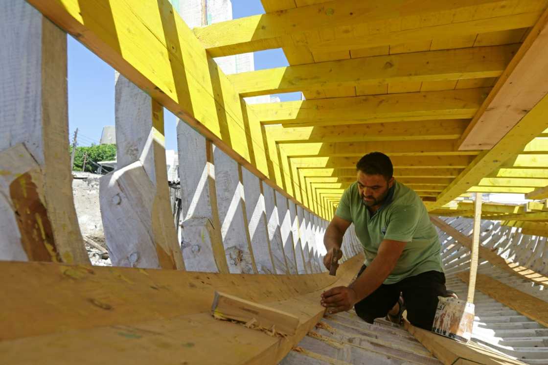 Khaled Bahlawan hammers nails in a wooden boat at his boatyard in Arwad, tough work that many young people now don't want to do