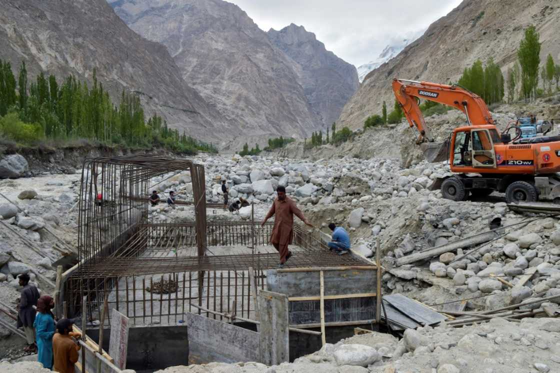 Construction workers build a temporary bridge in Hassanabad after the village's main bridge was destroyed in the flood Construction workers build a temporary bridge in Hassanabad after the village's main bridge was destroyed in the flood