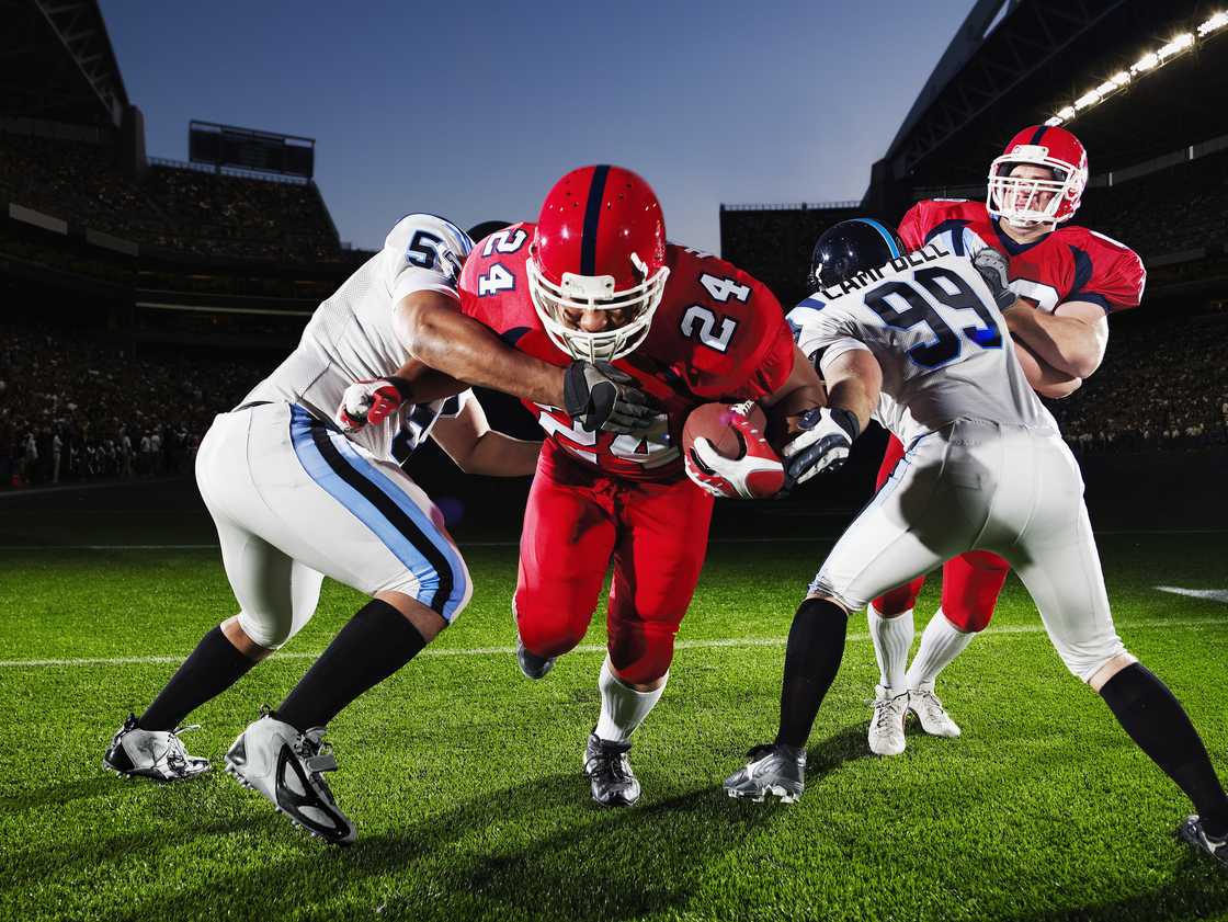 A group of football players sprinting on a field during a match. A group of football players sprinting on a field during a match.