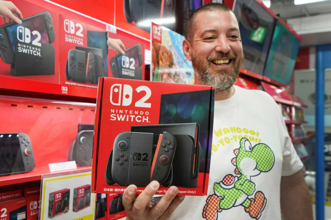 A French customer living in Tokyo smiles as he shows off a Nintendo Switch 2 bought at an electronics retailer A French customer living in Tokyo smiles as he shows off a Nintendo Switch 2 bought at an electronics retailer
