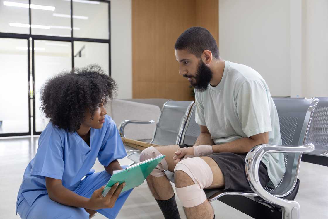 An African nurse is examining tendinitis on the knee injury An African nurse is examining tendinitis on the knee injury