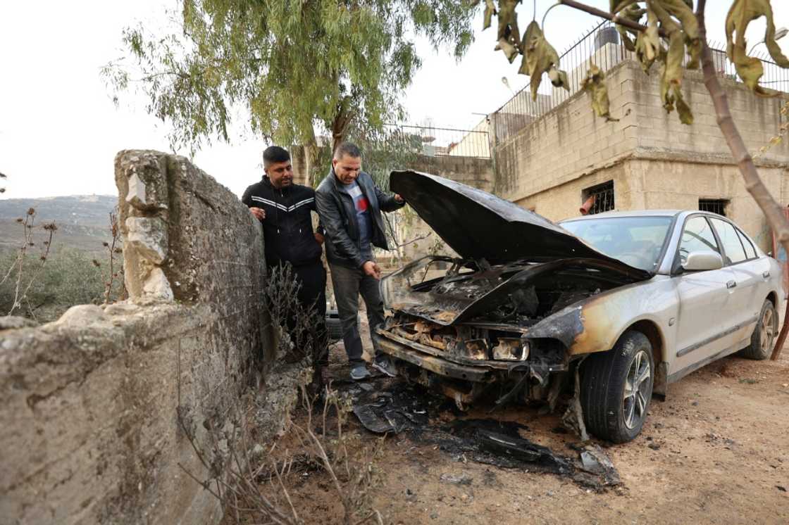 Palestinian men inspect a burned out car which they said it was set ablaze by Israeli settlers overnight Palestinian men inspect a burned out car which they said it was set ablaze by Israeli settlers overnight