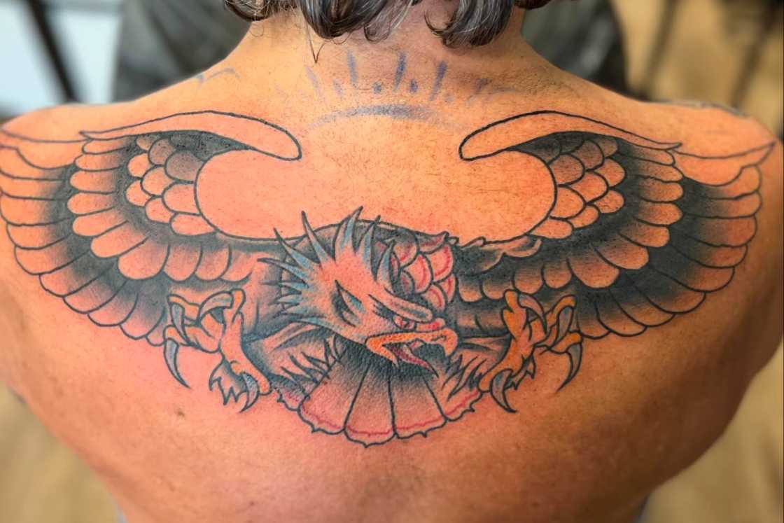 A man is having an eagle tattoo on his upper back A man is having an eagle tattoo on his upper back
