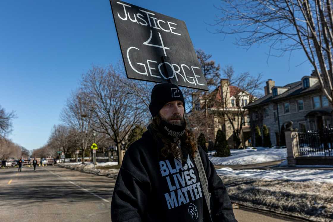 A man holds a placard outside the Minnesota governor's residence during a protest on March 6, 2021; a UN group of experts was appointed after Floyd's murder to investigate global systemic racism A man holds a placard outside the Minnesota governor's residence during a protest on March 6, 2021; a UN group of experts was appointed after Floyd's murder to investigate global systemic racism
