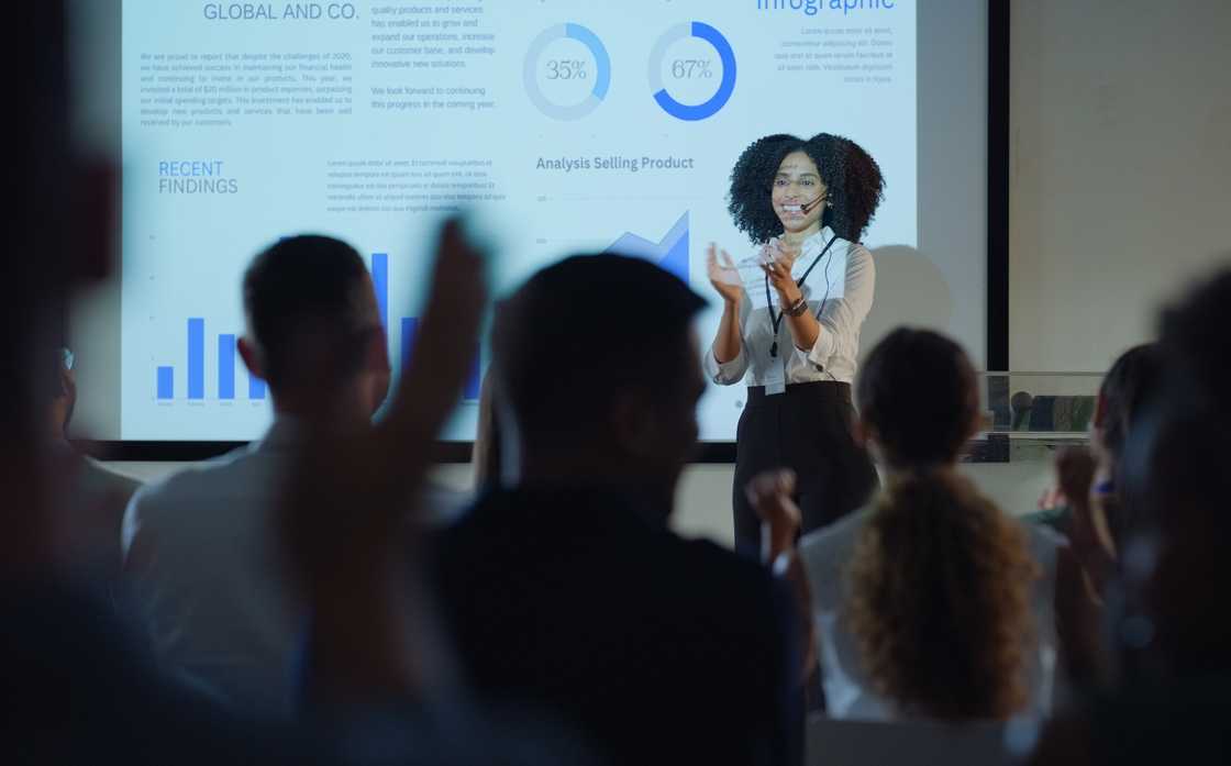 A woman trainer speaking to a crowd with confidence. A woman trainer speaking to a crowd with confidence.