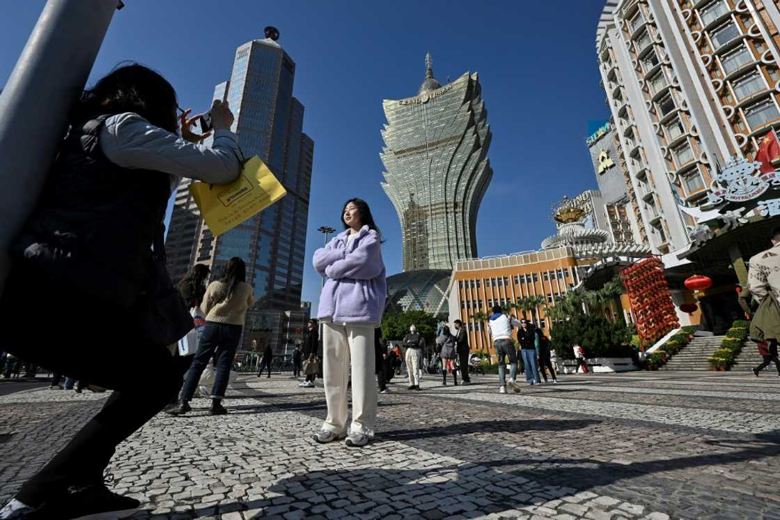 Chinese tourists take photos outside the Grand Lisboa Casino complex in Macau Chinese tourists take photos outside the Grand Lisboa Casino complex in Macau