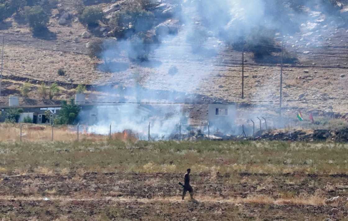 A Kurdish peshmerga fighter walks as smoke billows in the area of Zargwez, outside the Iraqi city of Sulaimaniyah, where several exiled left-wing Iranian Kurdish parties maintain offices A Kurdish peshmerga fighter walks as smoke billows in the area of Zargwez, outside the Iraqi city of Sulaimaniyah, where several exiled left-wing Iranian Kurdish parties maintain offices