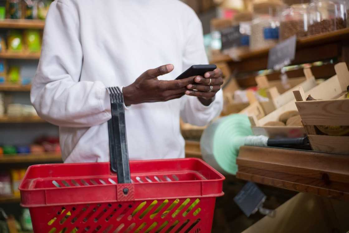 A young man stares at his phone at the supermarket.