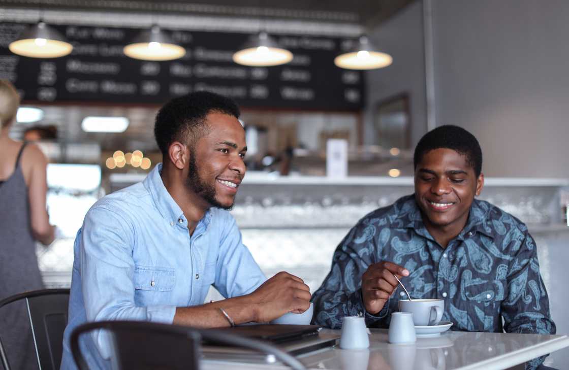 Two people smile and chat over drinks at a café table. Two people smile and chat over drinks at a café table.