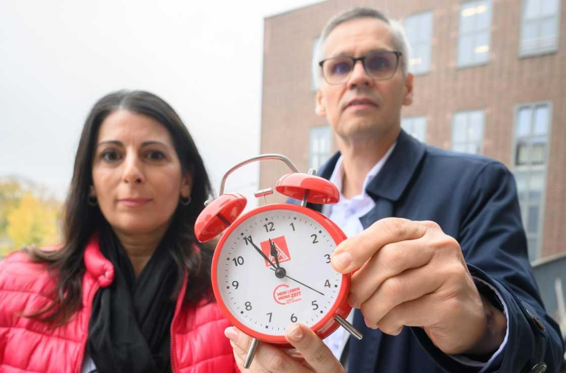 An alarm clock warning it's 'five minutes to high noon' at VW, held up by works council chief Daniela Cavallo and metalworkers union negotiator Thorsten Groeger An alarm clock warning it's 'five minutes to high noon' at VW, held up by works council chief Daniela Cavallo and metalworkers union negotiator Thorsten Groeger