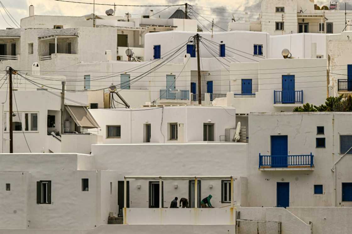 Workers renovate a traditional white Cycladic house on the Greek island of Paros Workers renovate a traditional white Cycladic house on the Greek island of Paros