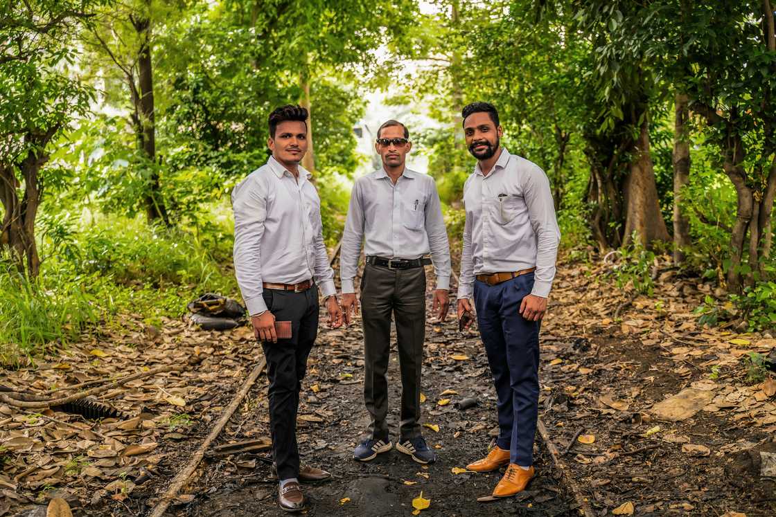 Three men wearing black, jungle green, and navy blue dress pants